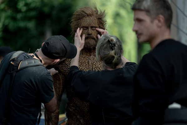 Alexander Skarsgard stands on the set of Wicker in his woven prosthetics having his makeup adjusted by lead makeup...